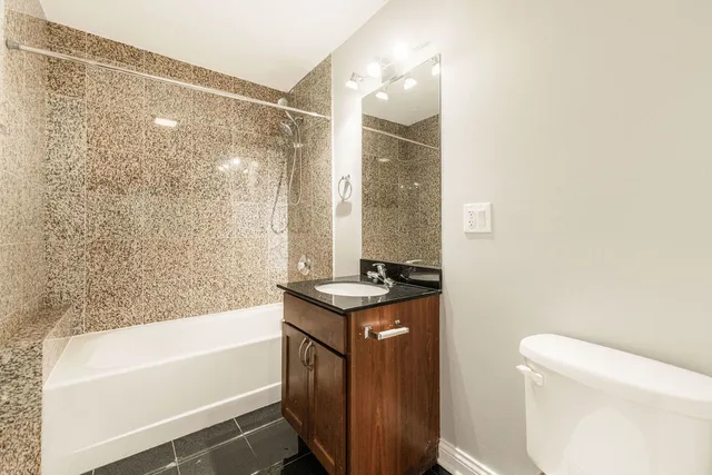 a bathroom with a granite countertop sink a toilet and bathtub
