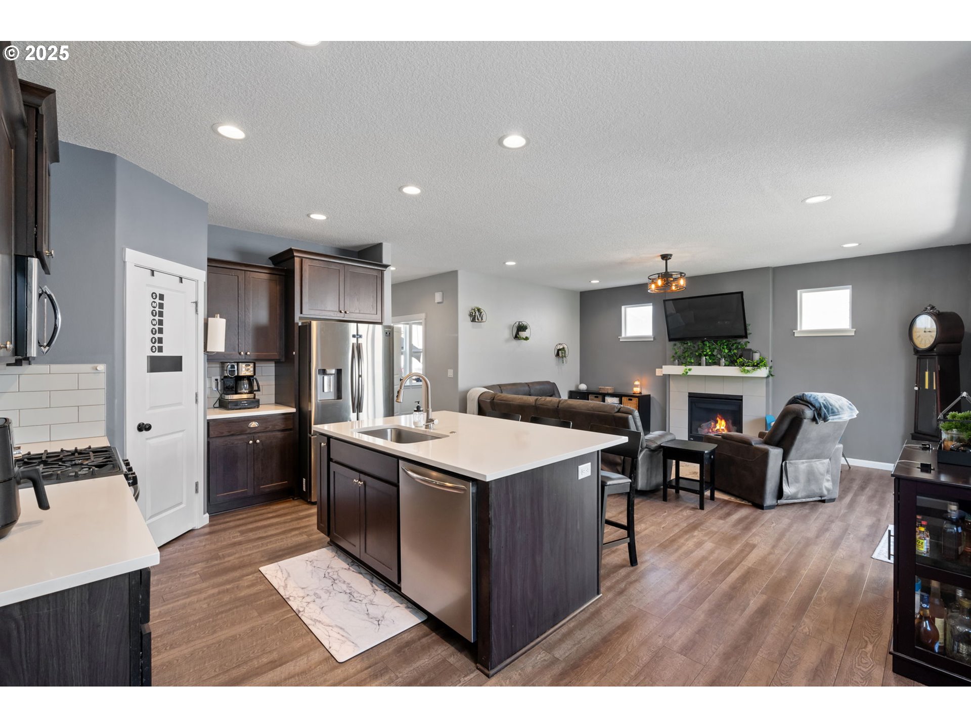2820 Southeast Baker Avenue Gresham, OR 97080 - Photo 10 of 33 a kitchen with stainless steel appliances kitchen island granite countertop a refrigerator a stove a sink a dining table and chairs with wooden floor