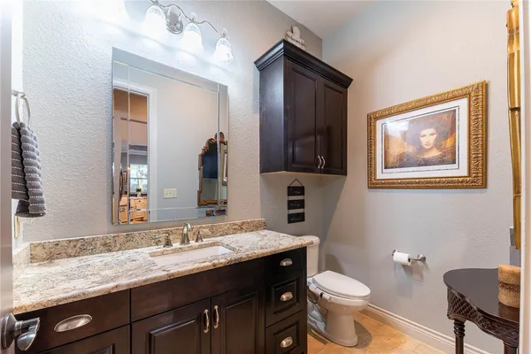 a bathroom with a granite countertop toilet sink and mirror