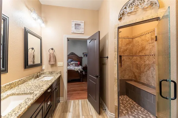 a en suite bathroom with a granite countertop sink and a shower