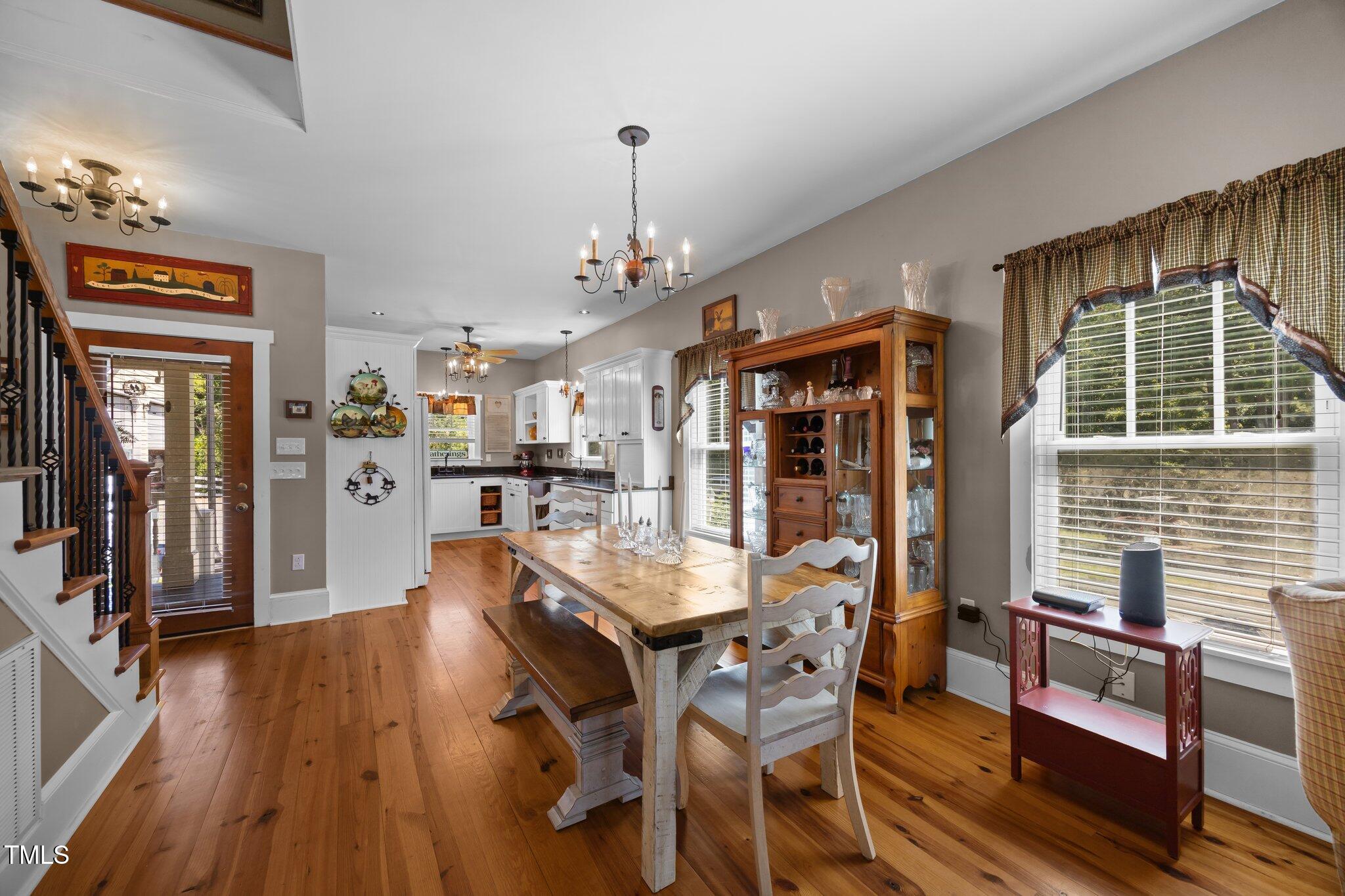 4050 Culbreth Road Stem, NC 27581 - Photo 17 of 46 a dining room with wooden floor a chandelier a wooden table and chairs