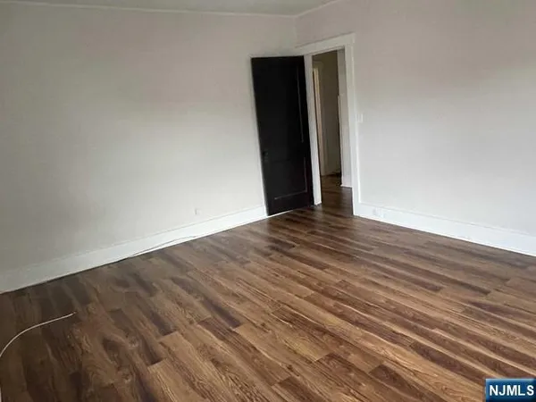 a view of an empty room with wooden floor and closet