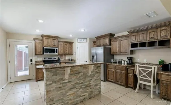 a kitchen with stainless steel appliances granite countertop a stove top oven a sink dishwasher a dining table and chairs with wooden floor