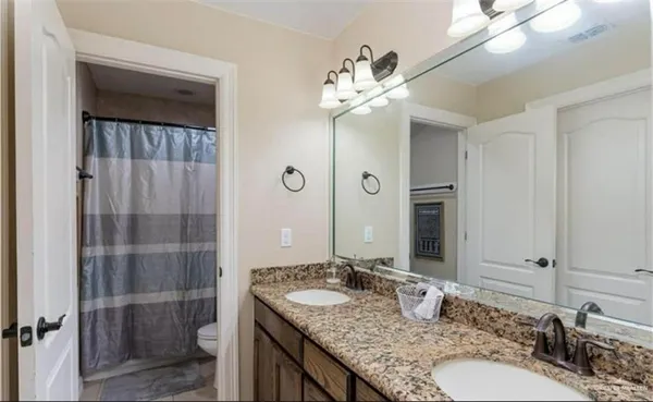 a bathroom with a granite countertop sink a toilet and shower