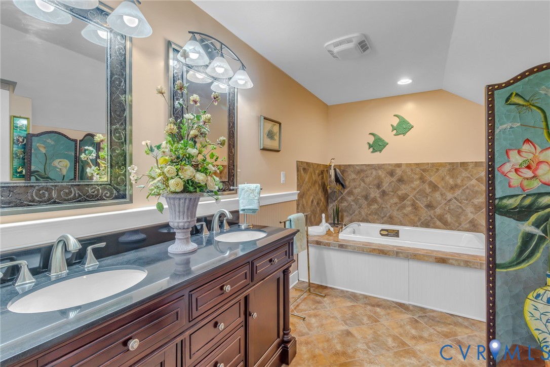 273 Sutton Avenue Reedville, VA 22539 - Photo 28 of 50 a spacious bathroom with a granite countertop tub a double vanity sink and a mirror