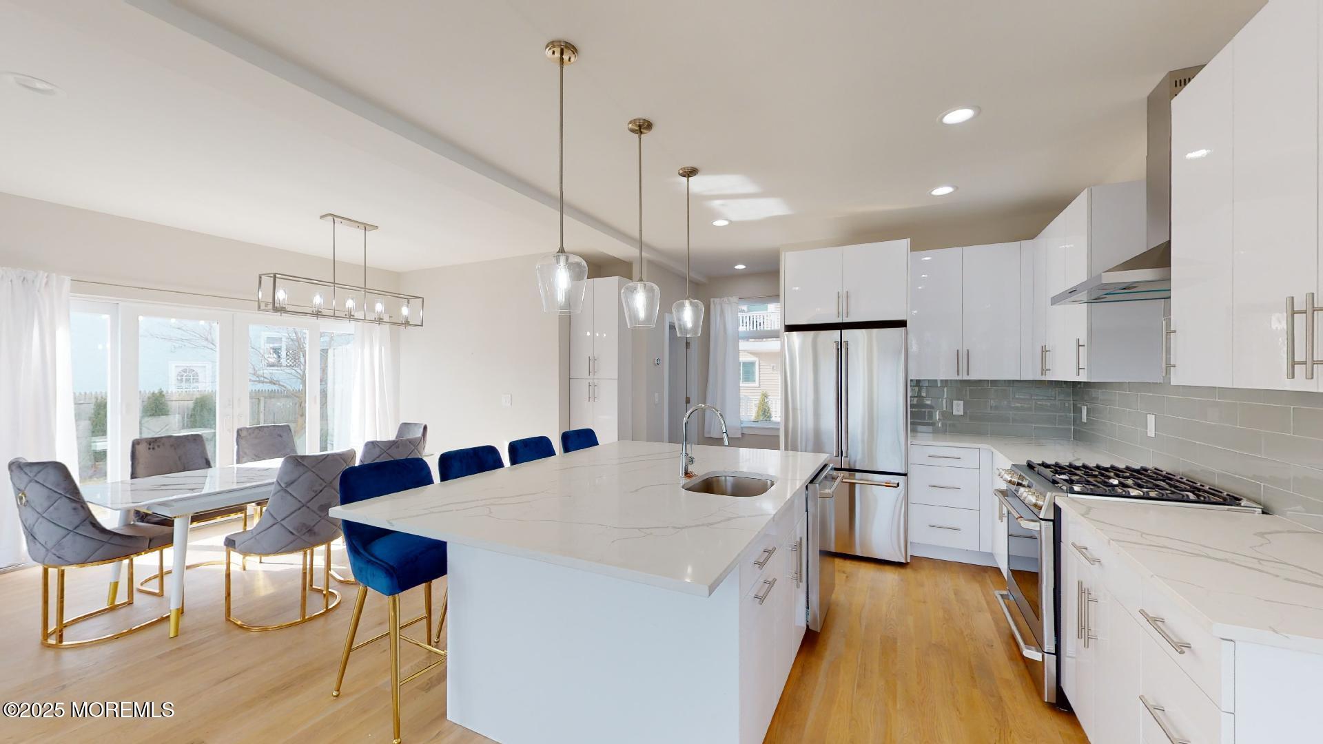 1 Howland Avenue Long Branch, NJ 07740 - Photo 5 of 22 an open kitchen with granite countertop a stove a sink a dining table and chairs with wooden floor