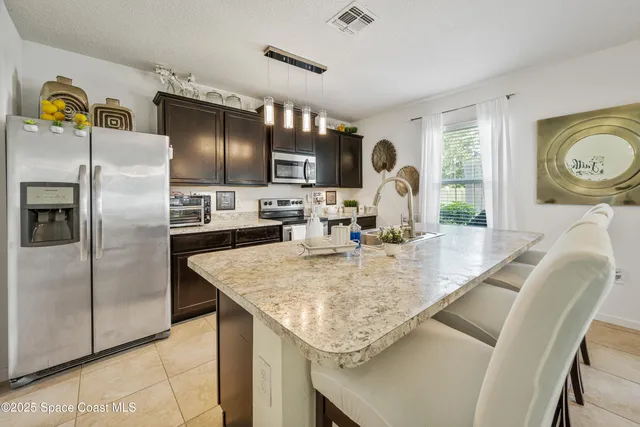 a kitchen with stainless steel appliances kitchen island granite countertop a sink stove and refrigerator
