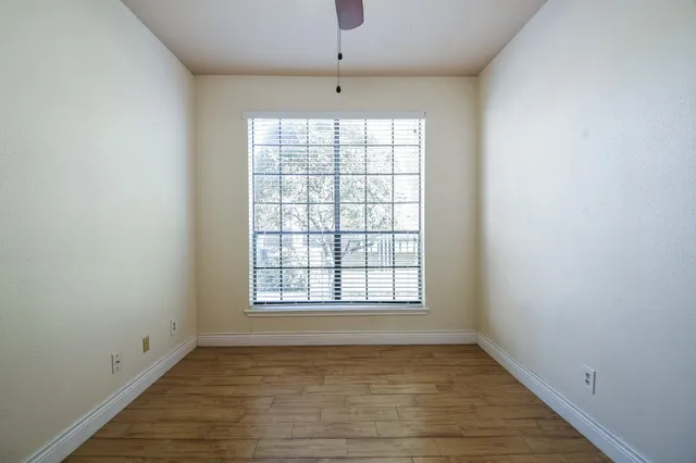 an empty room with wooden floor chandelier and windows