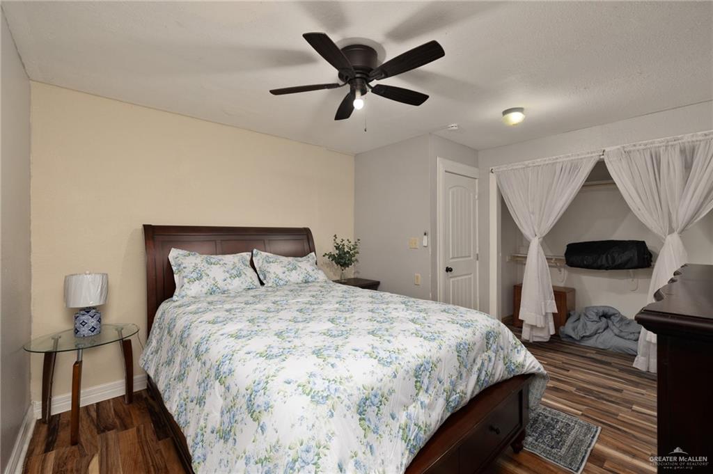 411 East 4th Street Rio Grande City, TX 78582 - Photo 9 of 12 Bedroom featuring wood-finish flooring, a ceiling fan with integrated lighting, and a built-in closet with shelving
