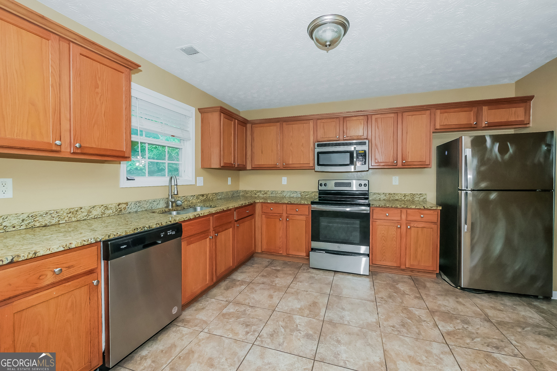 4468 Abram Way Conley, GA 30288 - Photo 6 of 17 a kitchen with granite countertop a refrigerator and a stove top oven
