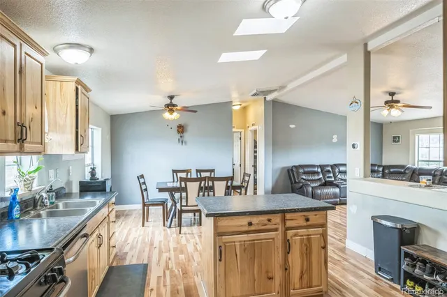 a kitchen with stainless steel appliances granite countertop a stove a sink dishwasher a dining table and chairs with wooden floor