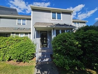a front view of a house with a yard and potted plants
