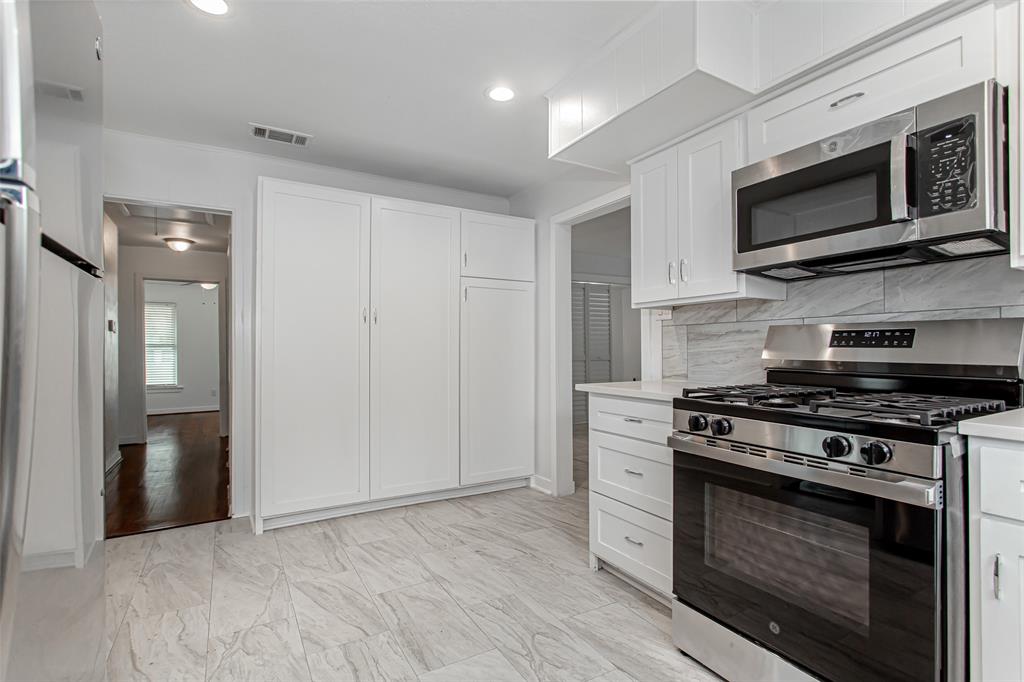 3311 Tooms Street Dallas, TX 75227 - Photo 13 of 38 a kitchen with stainless steel appliances a stove a microwave and cabinets
