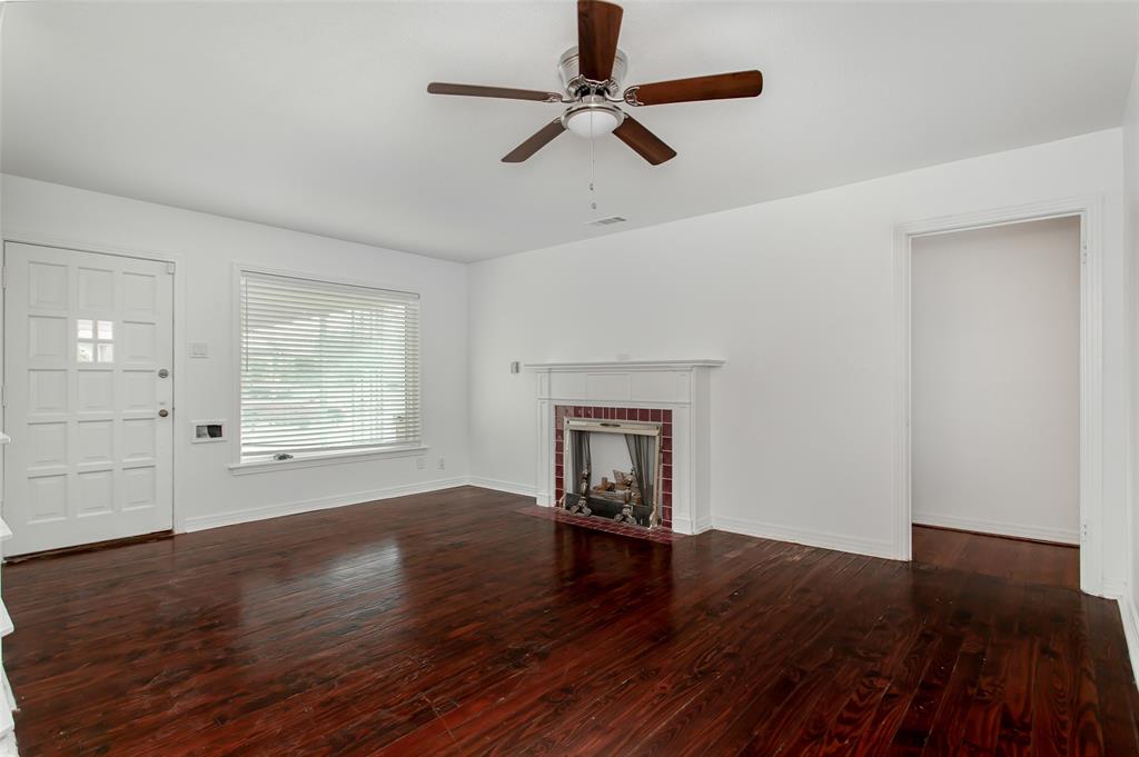 3311 Tooms Street Dallas, TX 75227 - Photo 7 of 38 an empty room with wooden floor fireplace and windows