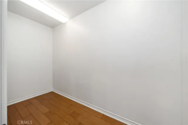 a view of a hallway with wooden floor and a bathroom