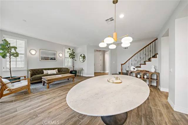a living room with couches a dining table and chairs with wooden floor