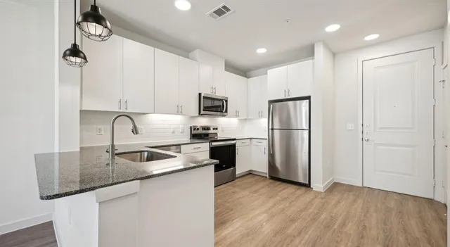 a kitchen with kitchen island a counter top space cabinets and stainless steel appliances