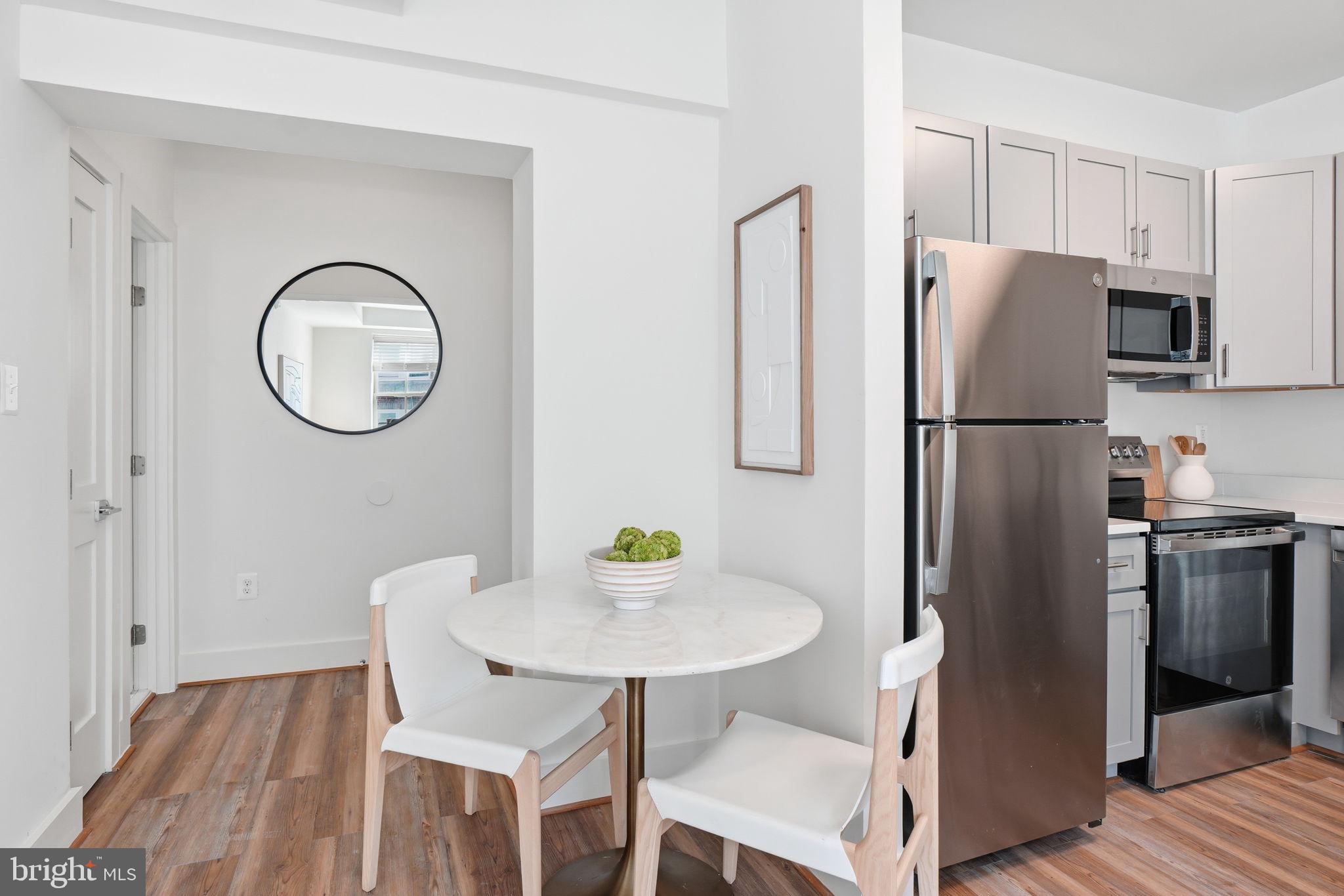 1451 Park Road Northwest, Unit 314 Washington, DC 20010 - Photo 14 of 22 a kitchen with stainless steel appliances granite countertop a refrigerator a stove a sink and a dining table with wooden floor