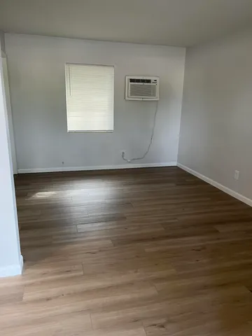 a view of an empty room with wooden floor and a window