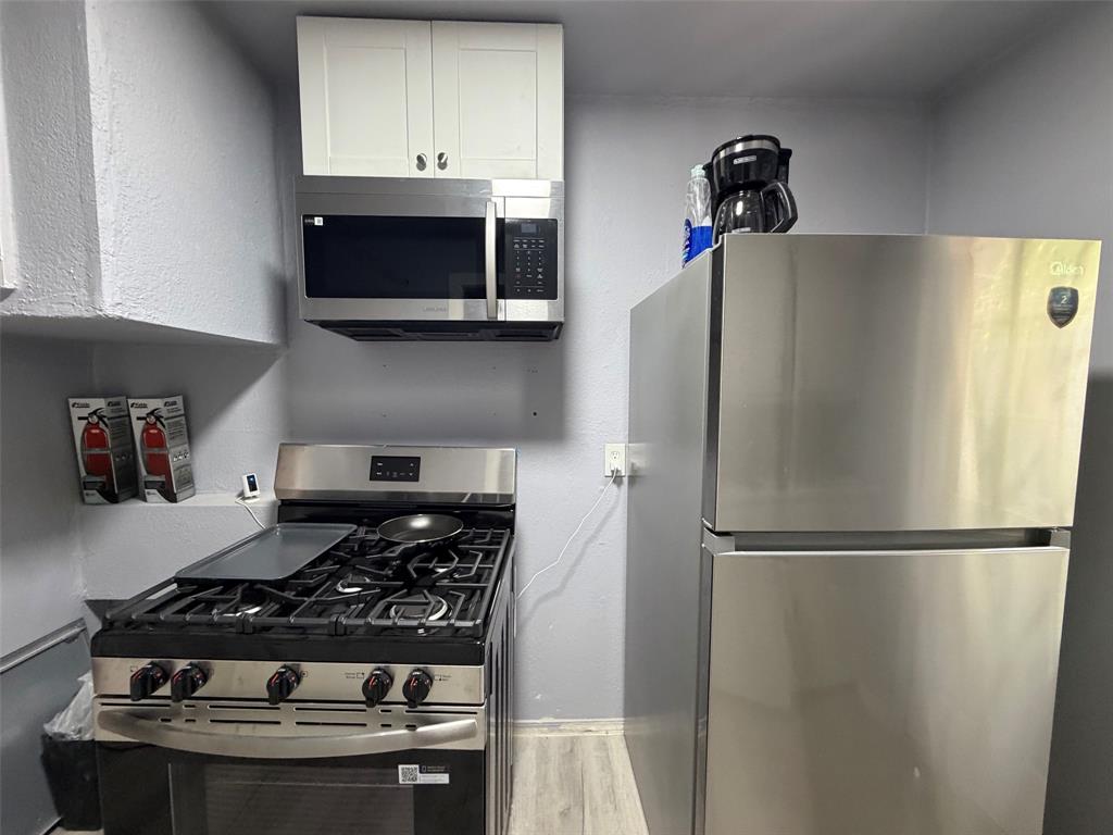 714 Southwest Dallas Street Grand Prairie, TX 75051 - Photo 4 of 27 Kitchen featuring stainless steel appliances, including a gas range, microwave, and refrigerator