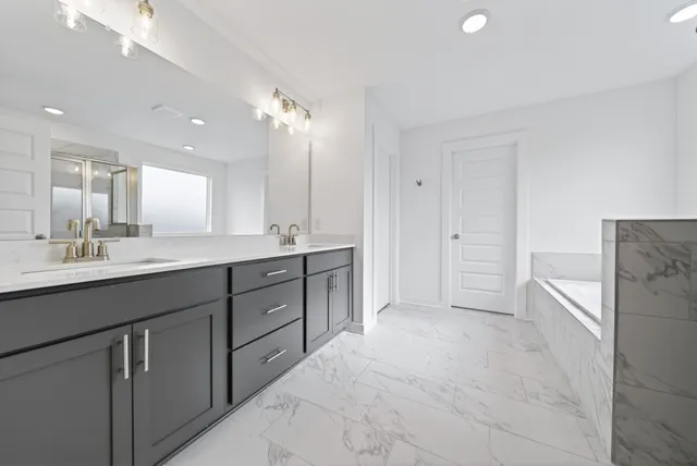 a spacious bathroom with a granite countertop sink mirror and a bathtub