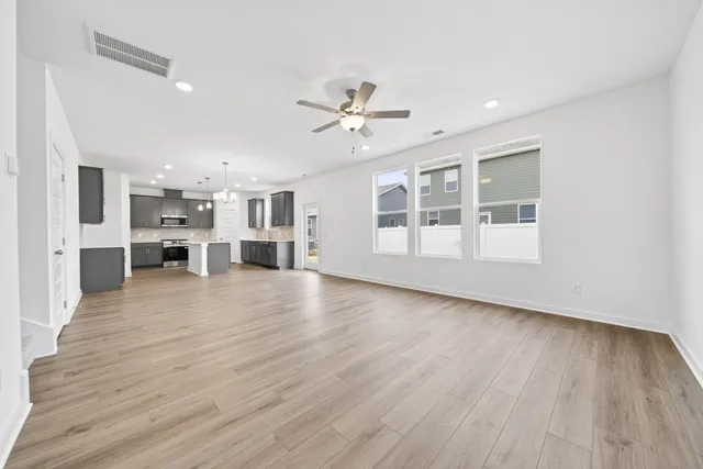 a view of a big room with wooden floor a kitchen view and a window