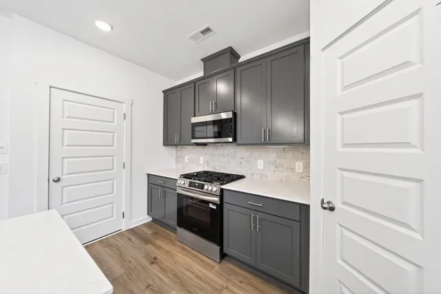 a kitchen with a refrigerator stove and white cabinets