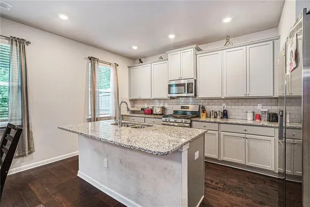 a kitchen with kitchen island granite countertop a sink window and cabinets