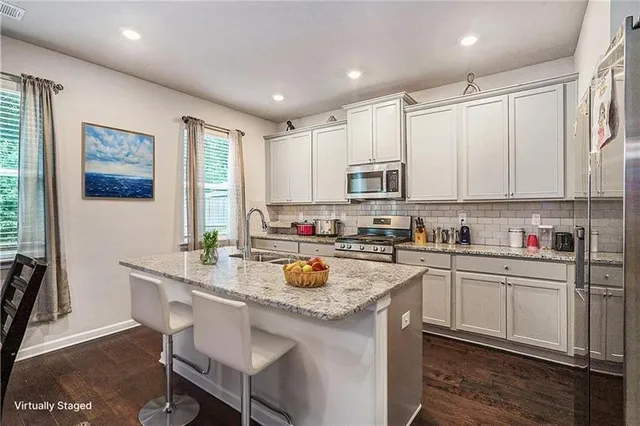 a kitchen with a sink stove and white cabinets with wooden floor
