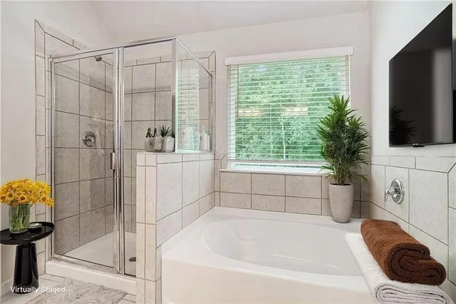 a bathroom with a tub a sink a window and a shower