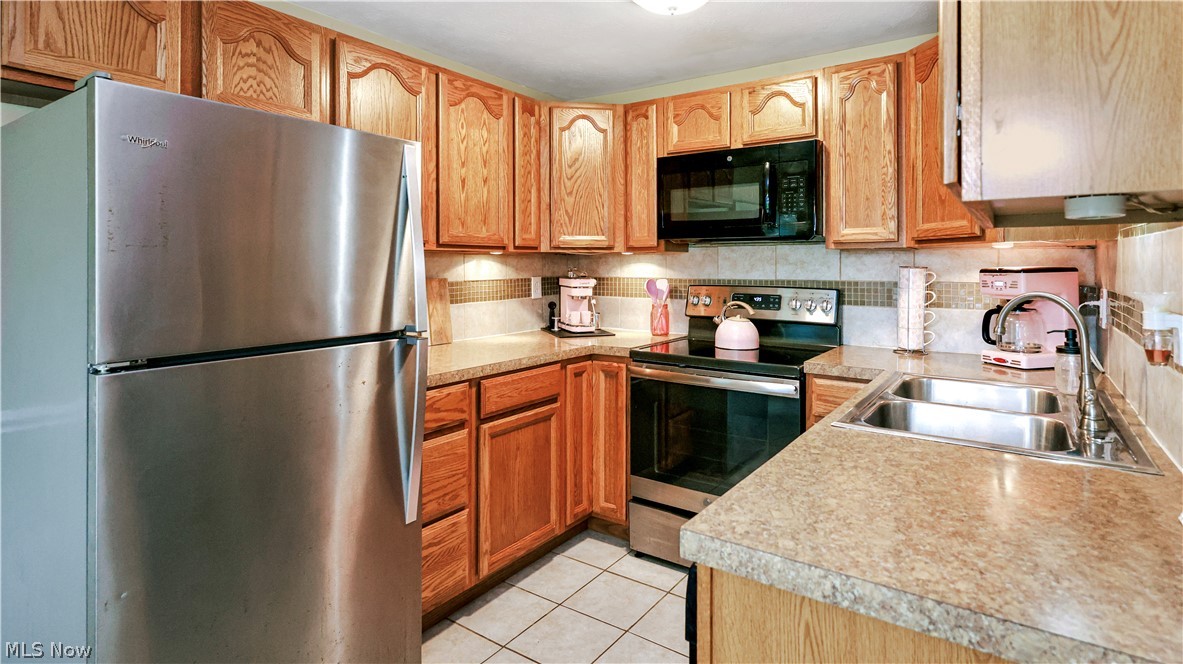 834 Wadsworth Road, Unit B1 Medina, OH 44256 - Photo 6 of 23 Kitchen featuring backsplash, appliances with stainless steel finishes, sink, and light tile flooring