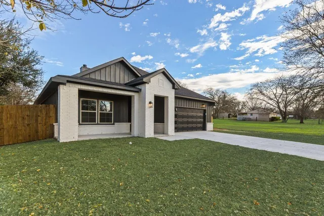 a view of a house with a big yard and large tree
