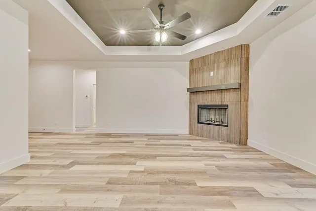 a view of an empty room with a fireplace and a chandelier fan