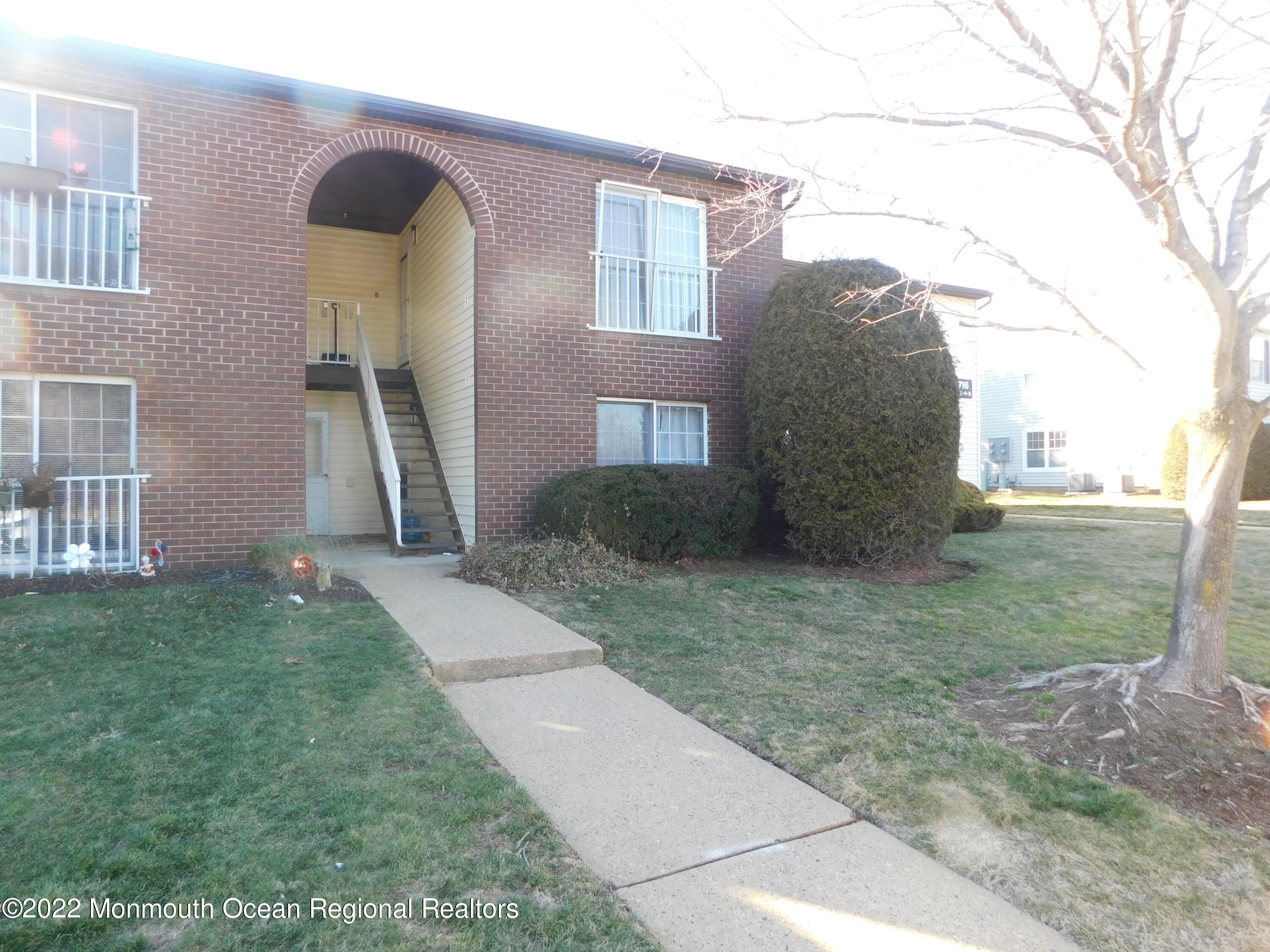 716 Zlotkin Circle, Unit 4 Freehold, NJ 07728 - Photo 10 of 10 a view of a brick house with many windows next to a yard