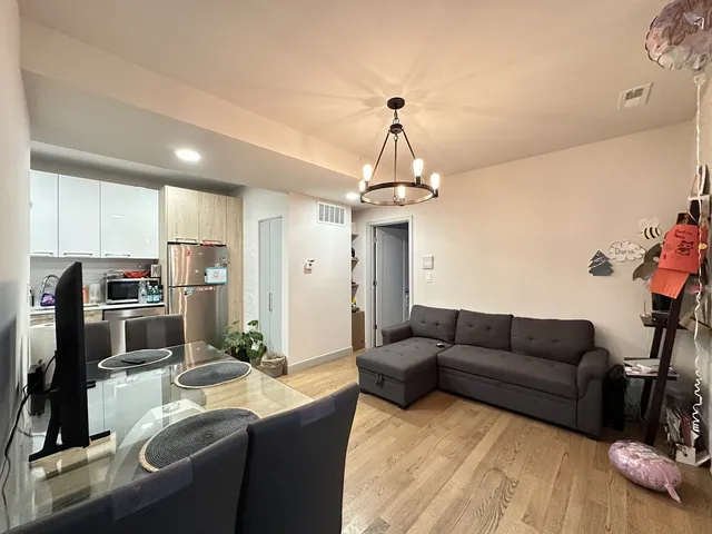 a living room with furniture a chandelier and kitchen view