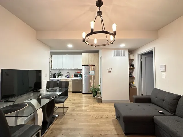 a living room with furniture a flat screen tv and kitchen view
