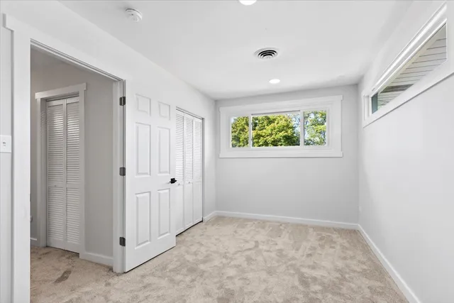 a view of an empty room with wooden floor and a ceiling fan