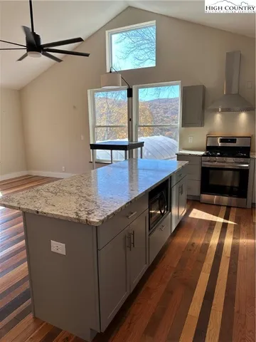 a view of a kitchen island a sink wooden floor and a window