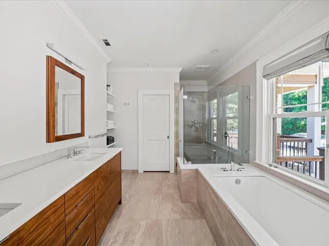 a bathroom with a bathtub double vanity sink and mirror