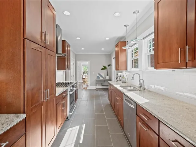 a large kitchen with stainless steel appliances granite countertop a refrigerator and a sink