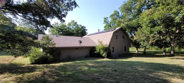 a view of a house with a yard and a large tree