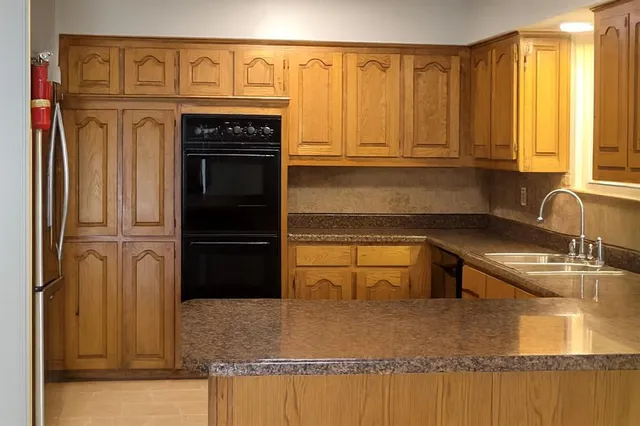 a view of a refrigerator in kitchen and an empty room with wooden floor