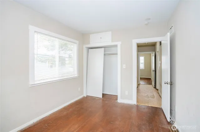a view of an empty room with wooden floor and a window