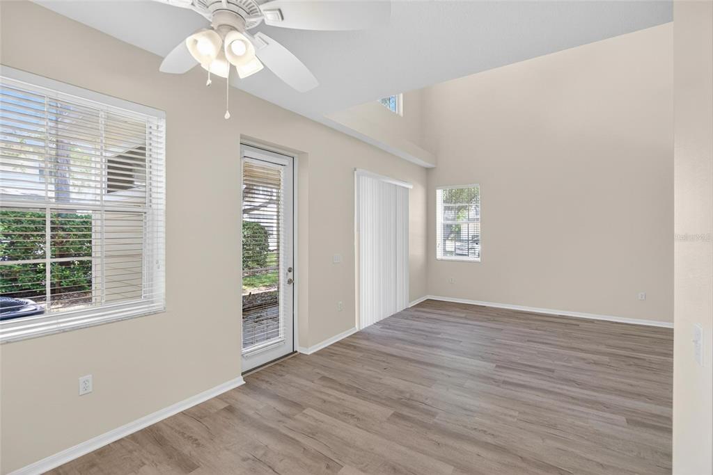 6418 Rosefinch Court, Unit 103 Lakewood Ranch, FL 34202 - Photo 12 of 48 an empty room with wooden floor chandelier fan and windows