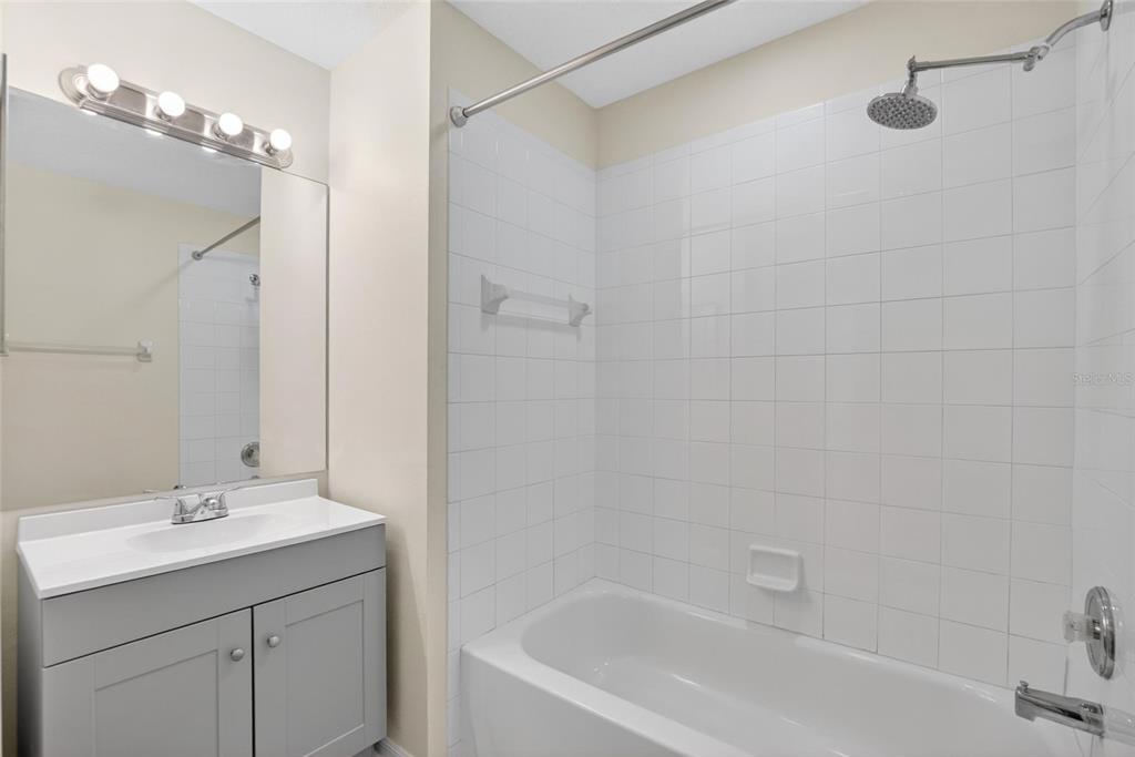 6418 Rosefinch Court, Unit 103 Lakewood Ranch, FL 34202 - Photo 25 of 48 a bathroom with a bathtub shower sink vanity and a mirror