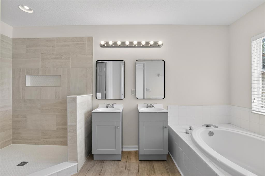 6418 Rosefinch Court, Unit 103 Lakewood Ranch, FL 34202 - Photo 30 of 48 a bathroom with a bathtub a mirror a sink and a shower