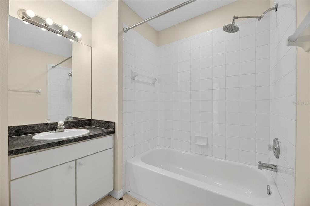 6418 Rosefinch Court, Unit 103 Lakewood Ranch, FL 34202 - Photo 33 of 52 a bathroom with a granite countertop sink a mirror a bathtub and shower