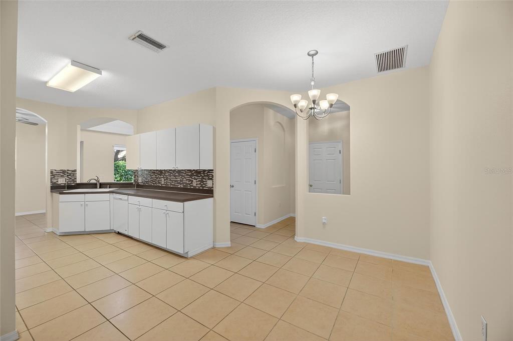 6418 Rosefinch Court, Unit 103 Lakewood Ranch, FL 34202 - Photo 10 of 52 a large white kitchen with a white cabinets and chandelier