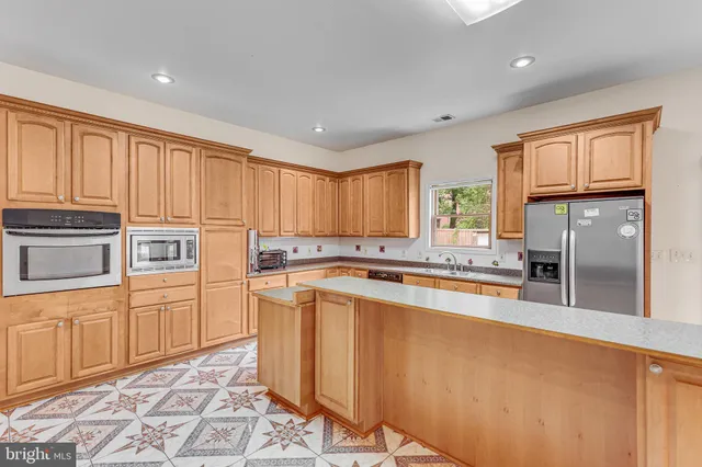 a kitchen with stainless steel appliances granite countertop a refrigerator a stove and a sink with cabinets
