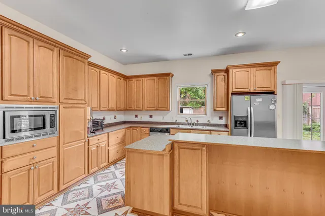 a large kitchen with stainless steel appliances granite countertop a stove a sink dishwasher and a refrigerator with wooden floor